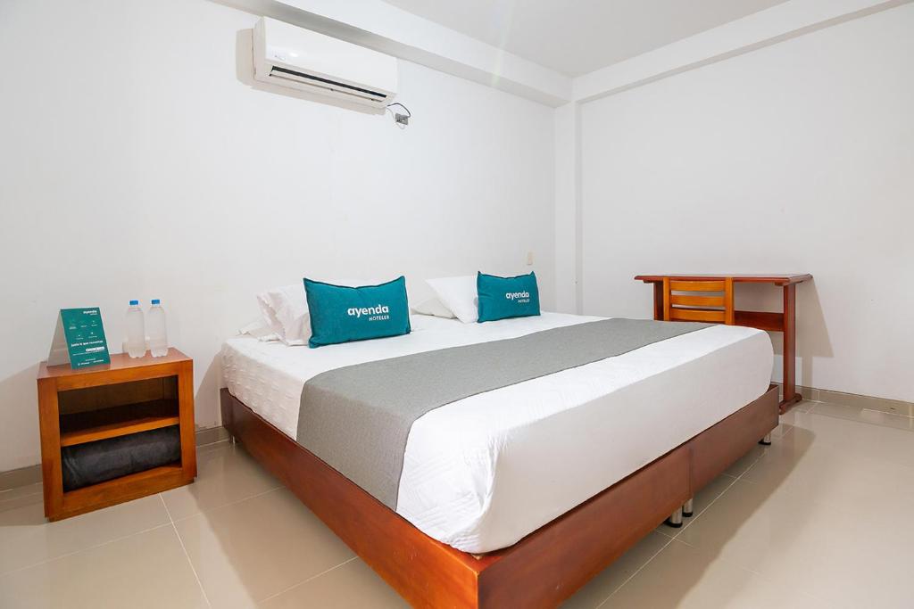 a bedroom with a large bed with blue pillows at Ayenda Juglar in Valledupar