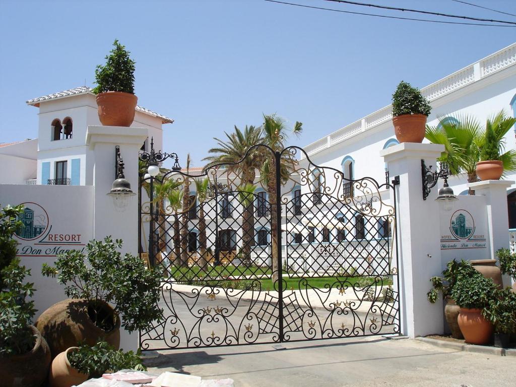 una puerta frente a una casa blanca con plantas en Hotel Hacienda Don Manuel, en Granja de Torrehermosa