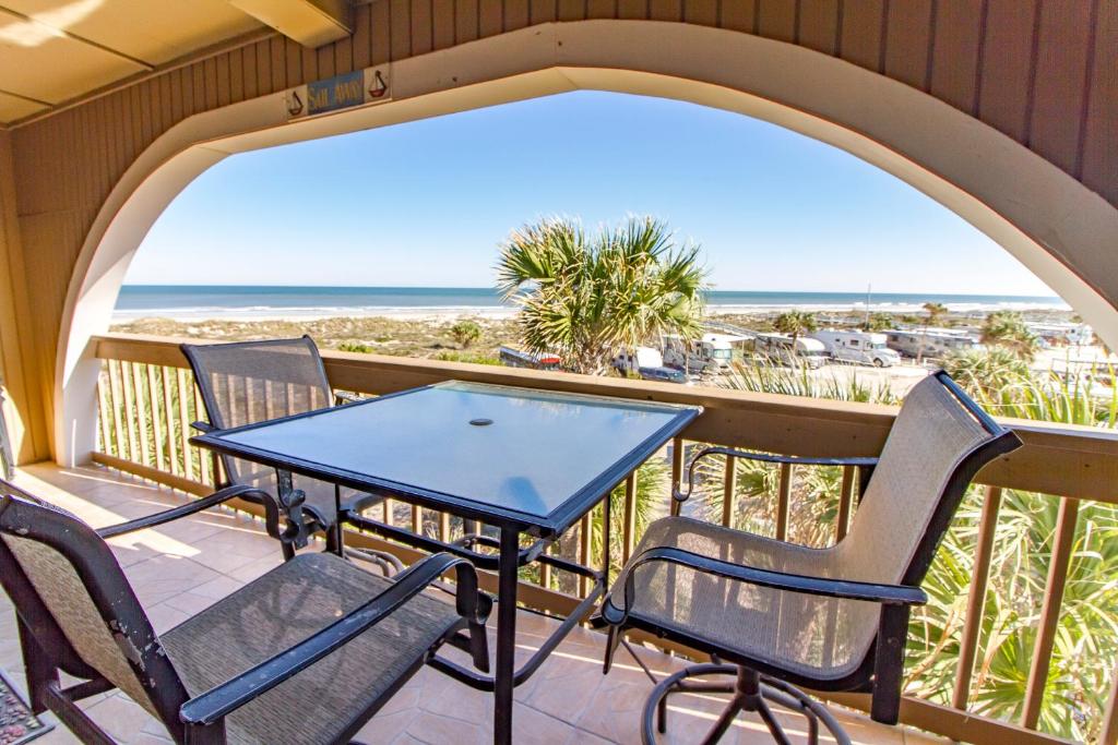 a table and chairs on a balcony with a view of the beach at Hibiscus Bravo in St. Augustine