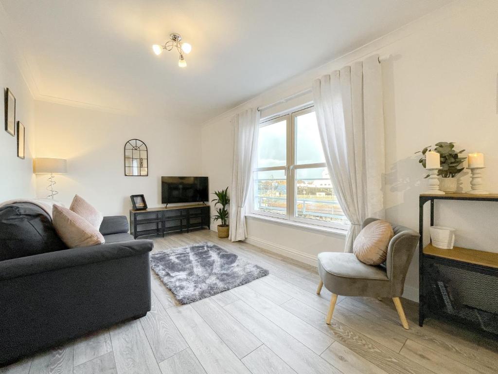 a living room with a couch and a tv and a window at Pier View Apartment in Oban