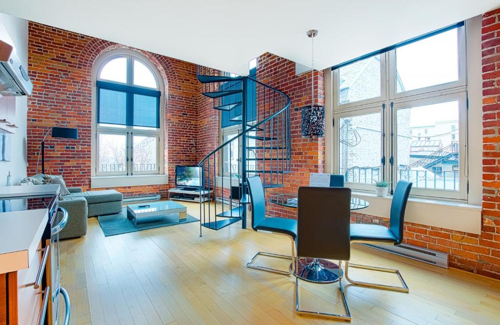 a living room with a brick wall and a spiral staircase at La Casa St-Jean - OLD QUEBEC in Quebec City