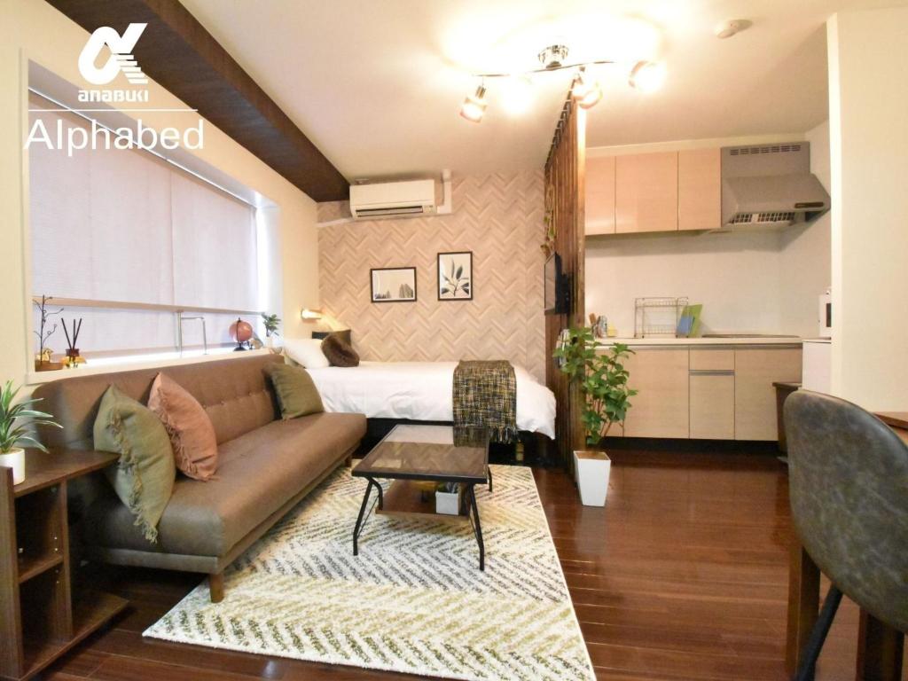 a living room with a couch and a bed at Alphabed Takamatsu Furujinmachi - Vacation STAY 11907 in Takamatsu