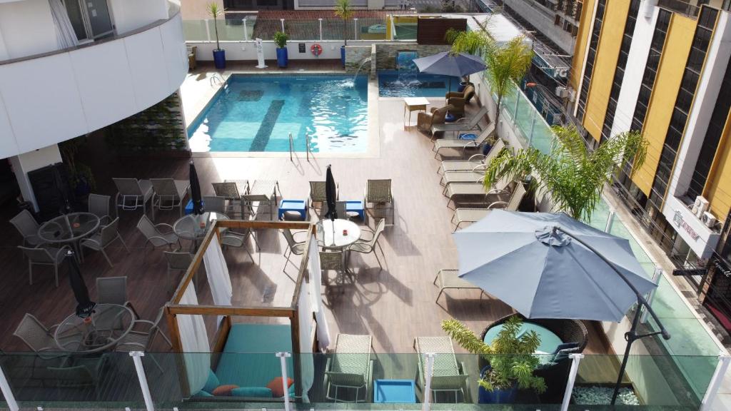 バウネアーリオ・コンボリウーにあるHotel Sibara SPA & Convençõesのプールの景色を望む客室で、椅子とパラソルが備わります。