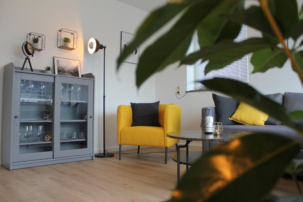 City Living near ICE/1&1/Fashion Outlet Montabaur في مونتابور: غرفة معيشة فيها كرسي اصفر وطاولة