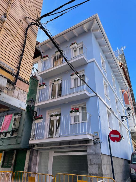 - un bâtiment blanc avec balcon dans une rue dans l'établissement APARTAMENTOS SAN JUAN de GAZTELUGATXE, à Bermeo