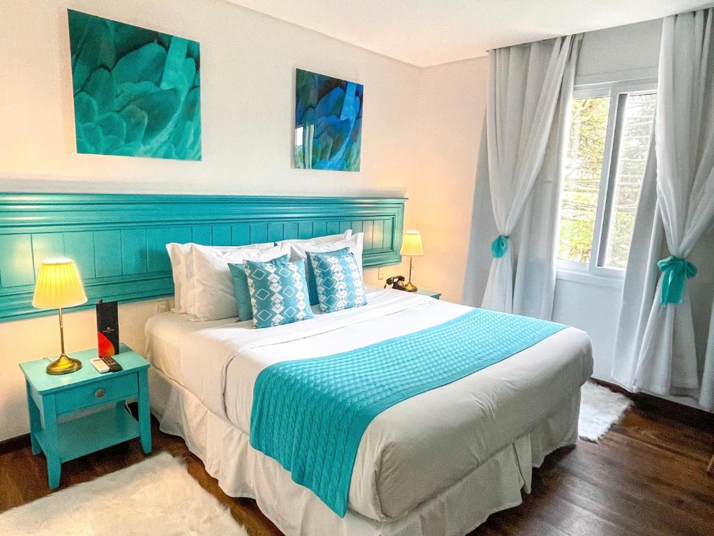 a bedroom with a large bed with a blue headboard at Flame Hotel Boutique Canela in Canela