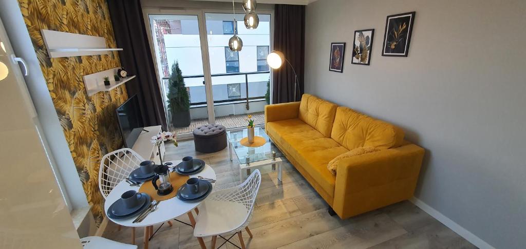 ein Wohnzimmer mit einem gelben Sofa und einem Tisch in der Unterkunft Apartament3City in Danzig