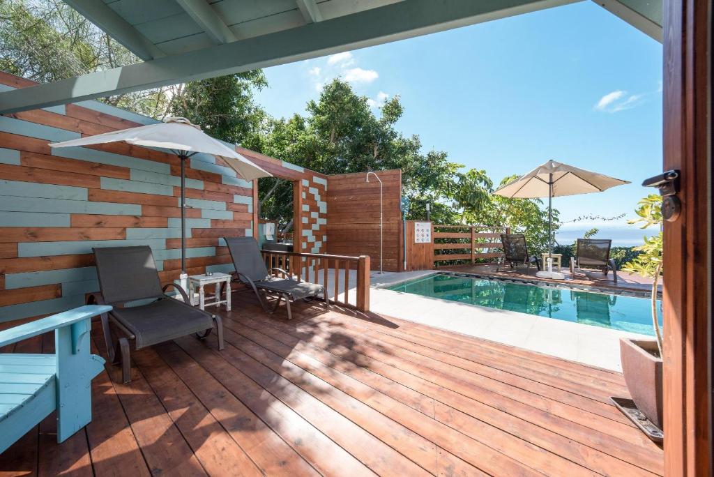una terraza de madera con piscina y sombrilla en Las Hermanas B en Guía de Isora