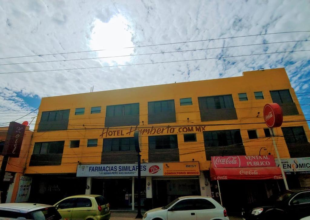 un edificio amarillo con coches estacionados frente a él en Hotel Humberto, en Tepic