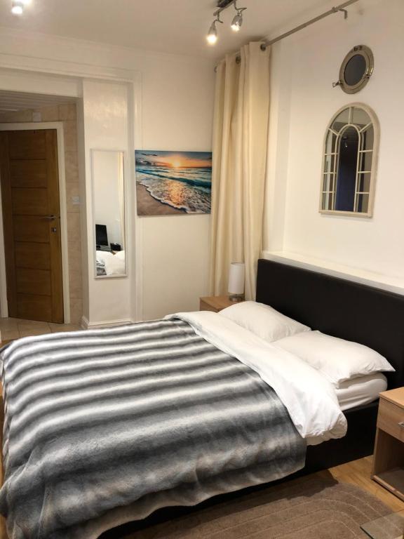 una camera da letto con un grande letto con una coperta a righe di Modern Apartment in Twickenham Highstreet a Twickenham
