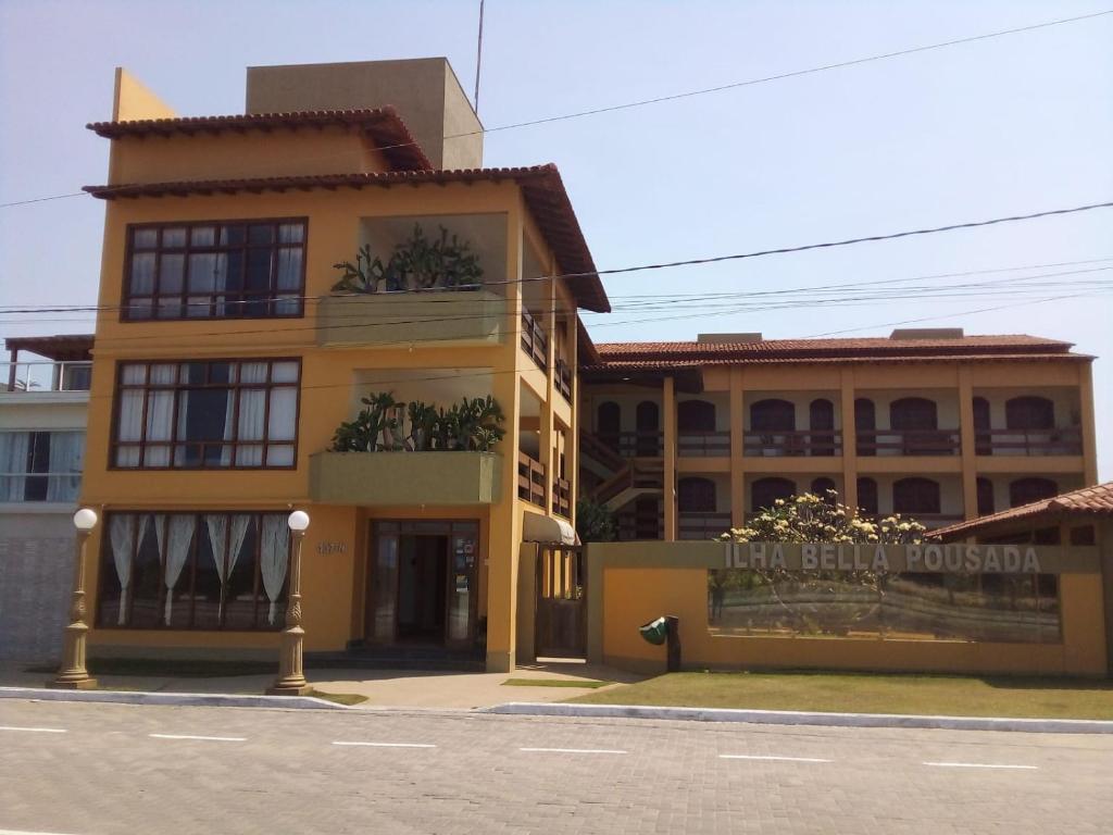 un edificio amarillo al lado de una calle en Pousada Ilha Bella, en Guriri