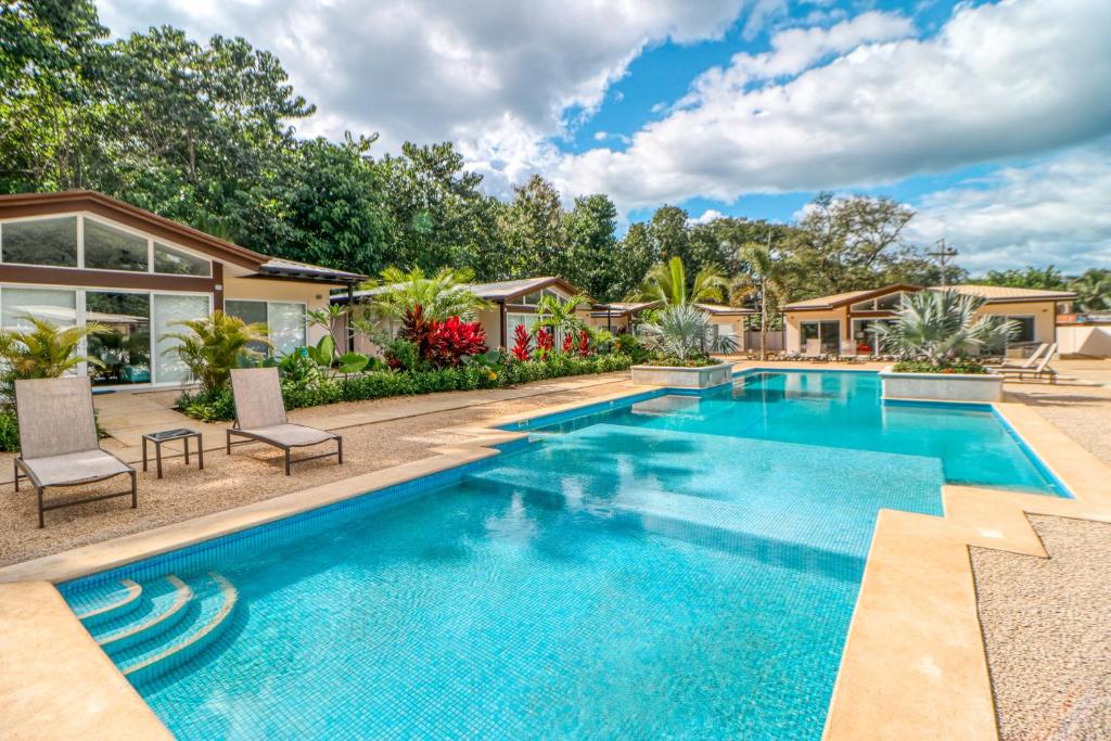 a swimming pool with chairs and a house at The Point in Playa Avellana