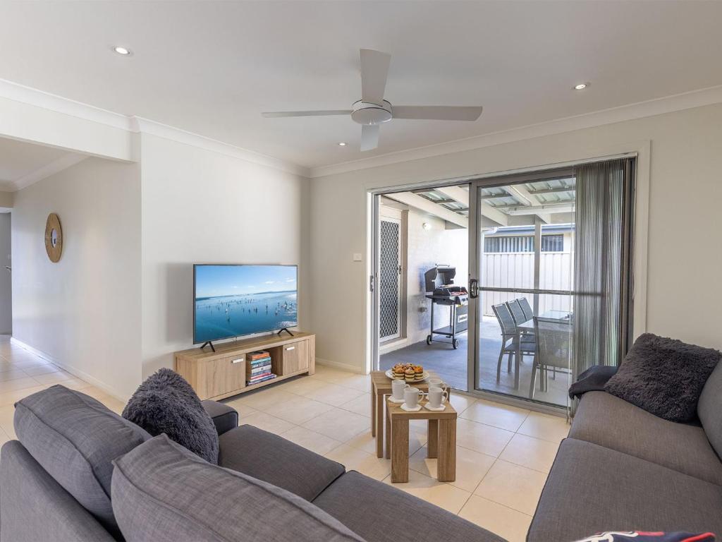 a living room with a couch and a flat screen tv at 15 Oasis Close Soldiers Point in Soldiers Point