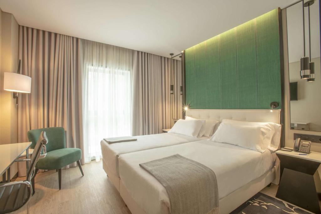 a hotel room with two beds and a television at NH Porto Jardim in Porto