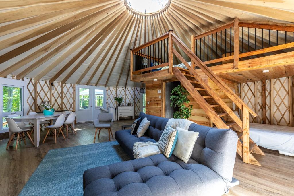 a living room with a blue couch and a wooden ceiling at Yourtes Glamping du Poisson Blanc in Notre-Dame-du-Laus