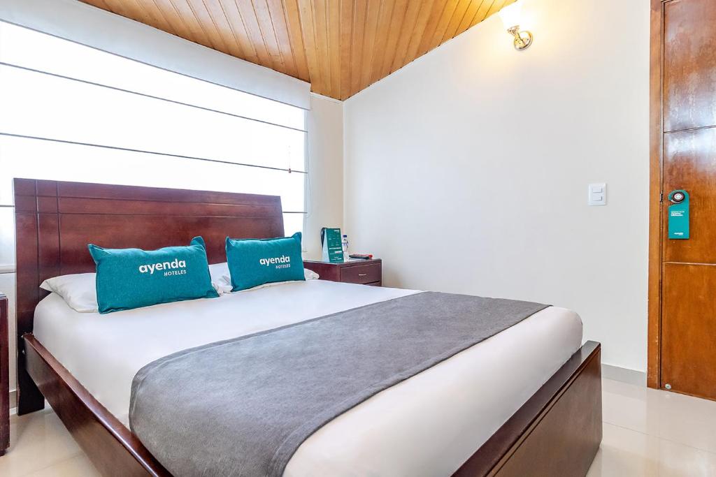 a bedroom with a large bed with two blue pillows at Ayenda Nabusimake in Bogotá
