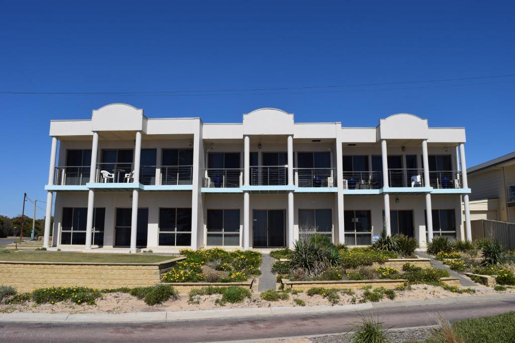 a white building with balconies on a street at Christies Seahorse Holiday Townhouses in Port Noarlunga