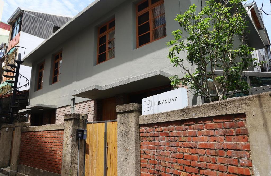 una casa con una pared de ladrillo y una puerta de madera en Humanlive, en Tainan