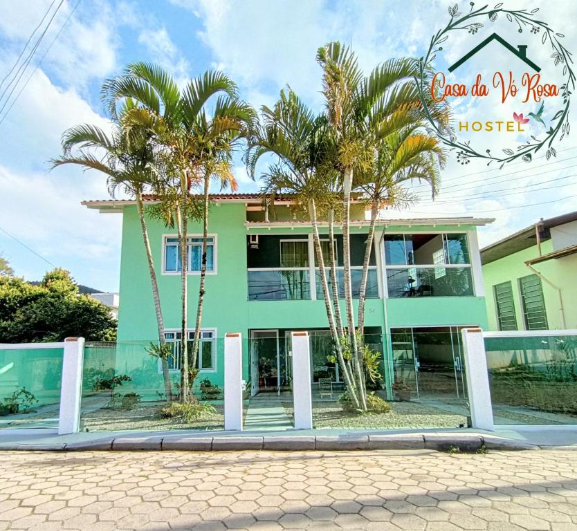 un edificio verde con palmeras delante en HOSTEL CASA DA VÓ ROSA en Governador Celso Ramos