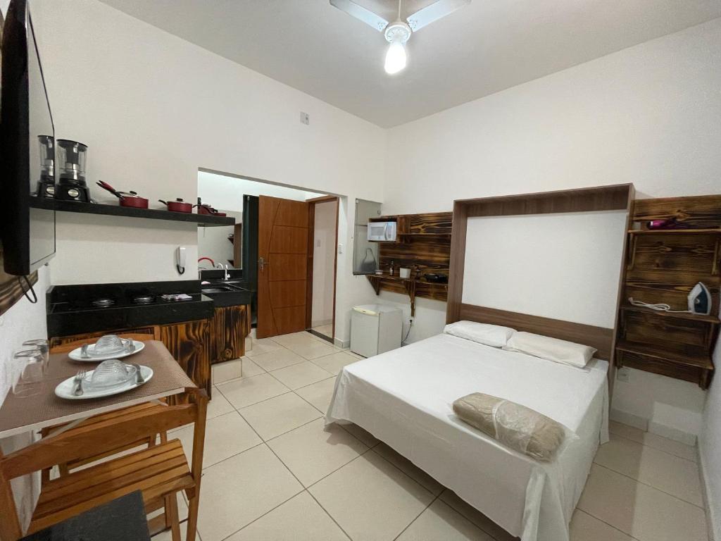 um quarto com uma cama e uma mesa em Suíte confortável no Centro de Caratinga em Caratinga