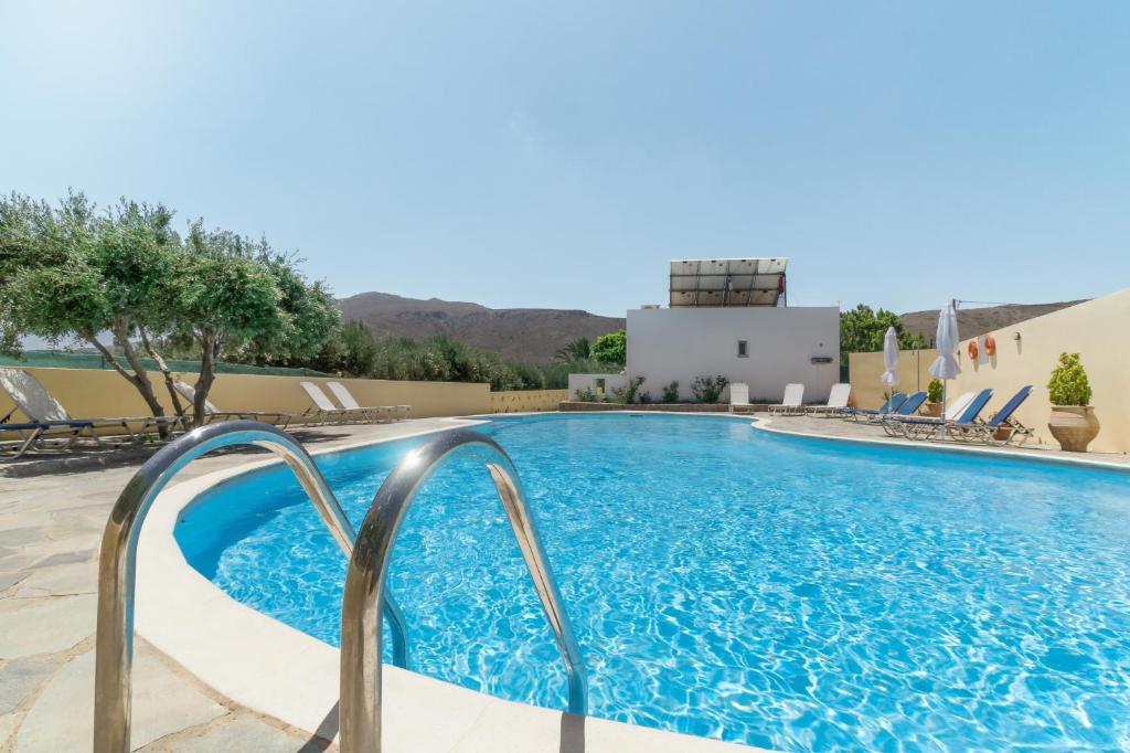 una piscina in un hotel con sedie e un edificio di Rousolakos Apartments a Paleocastro (Palekastron)
