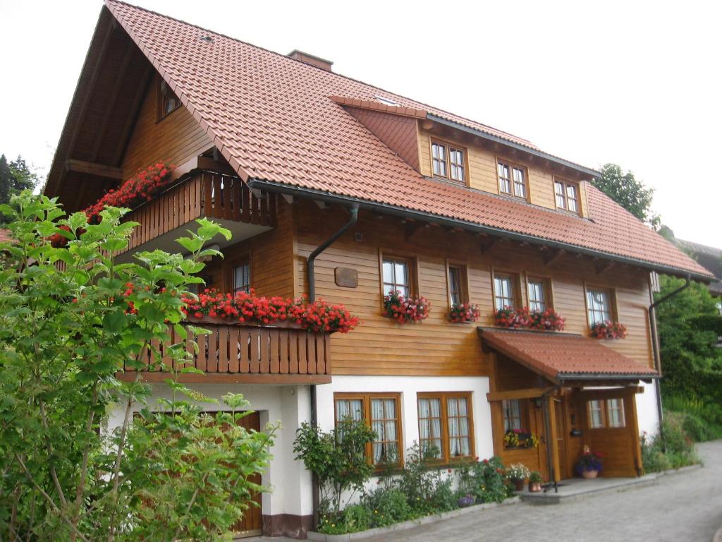 een houten huis met rode bloemen op de ramen bij Gästehaus Faller in Feldberg
