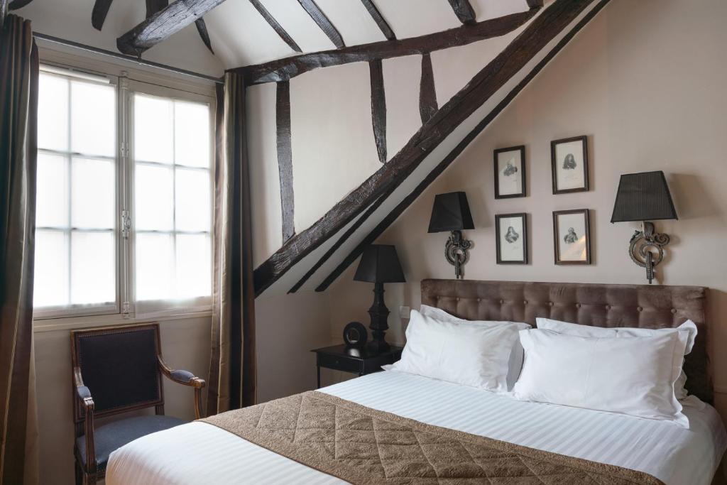 um quarto com uma cama grande e almofadas brancas em Hotel Saint-Louis Marais em Paris