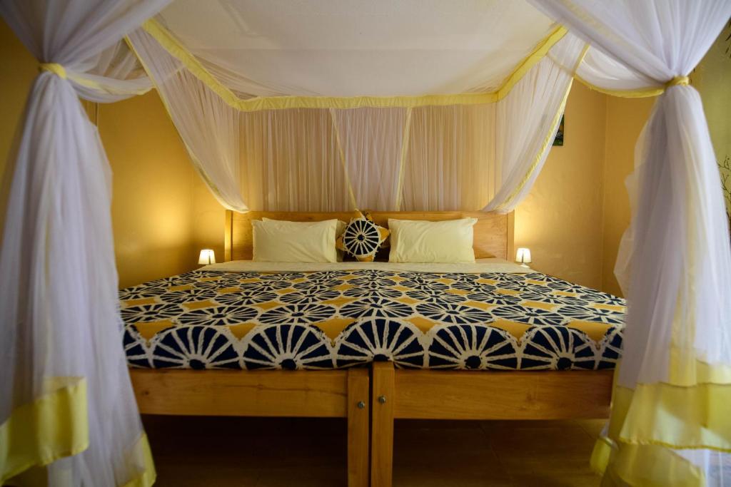a bedroom with a bed with a canopy at Cycad Entebbe Guest House in Entebbe