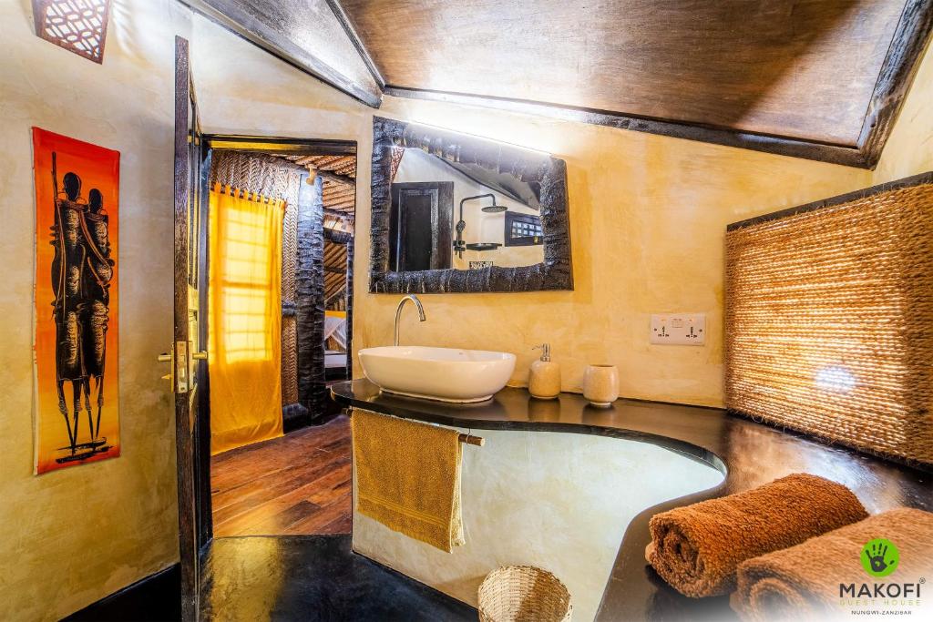 a bathroom with a bath tub and a sink at Makofi Guest House in Nungwi