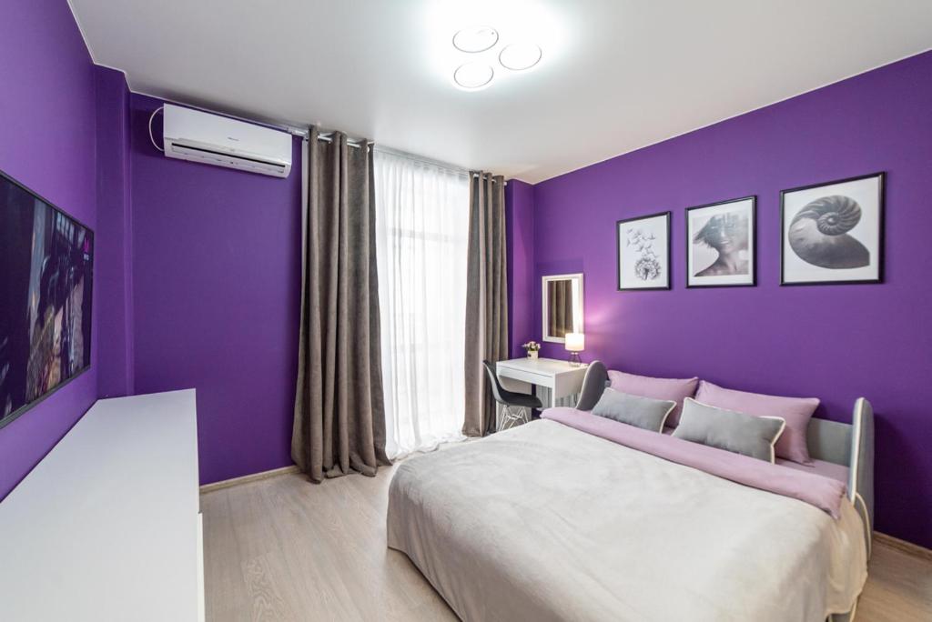 Dormitorio púrpura con cama y escritorio en "Sharm" Стильная студия на Броско, en Khabarovsk
