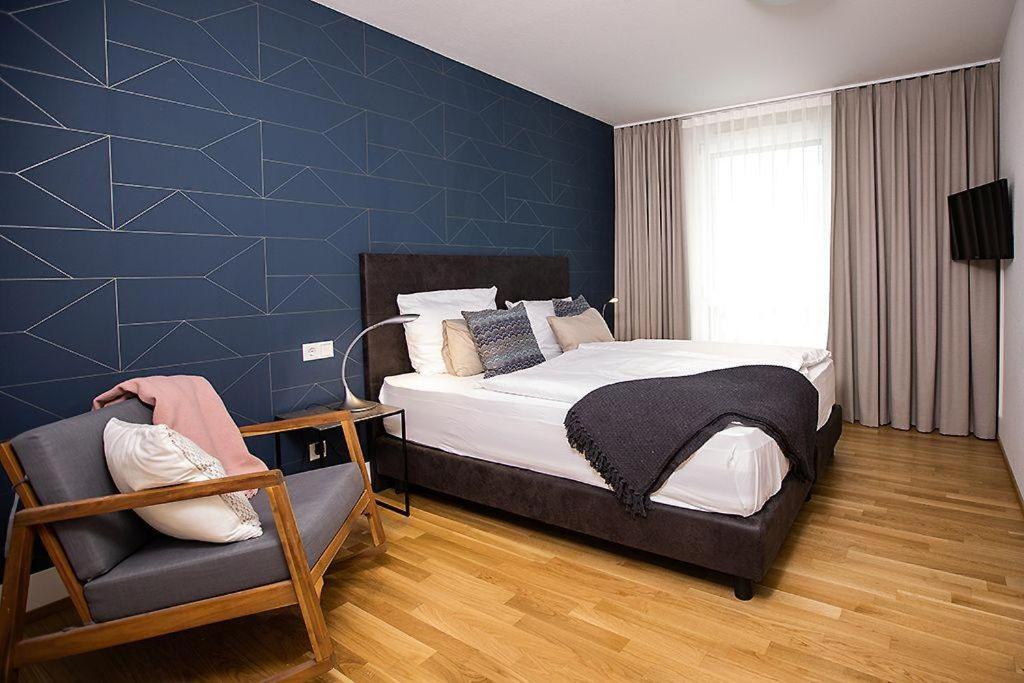1 dormitorio con 1 cama grande y 1 silla en Ferienwohnung-Saentis en Friedrichshafen