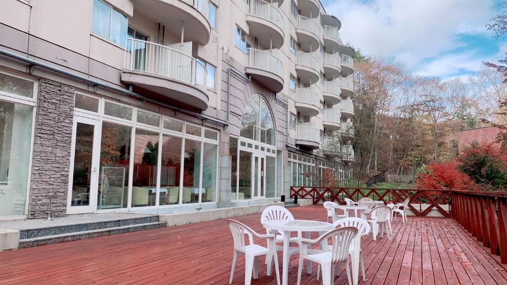 eine Terrasse mit weißen Tischen und Stühlen vor einem Gebäude in der Unterkunft Fujisan Garden Hotel in Yamanakako