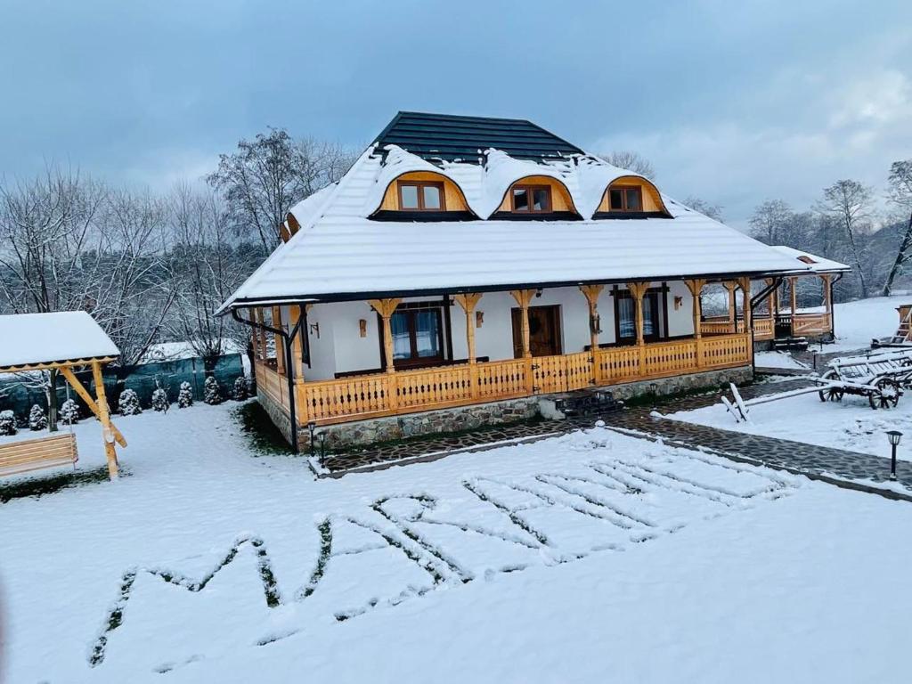una casa con un tetto innevato nella neve di Casa Moroșanului Vișeu de Sus a Vişeu de Sus