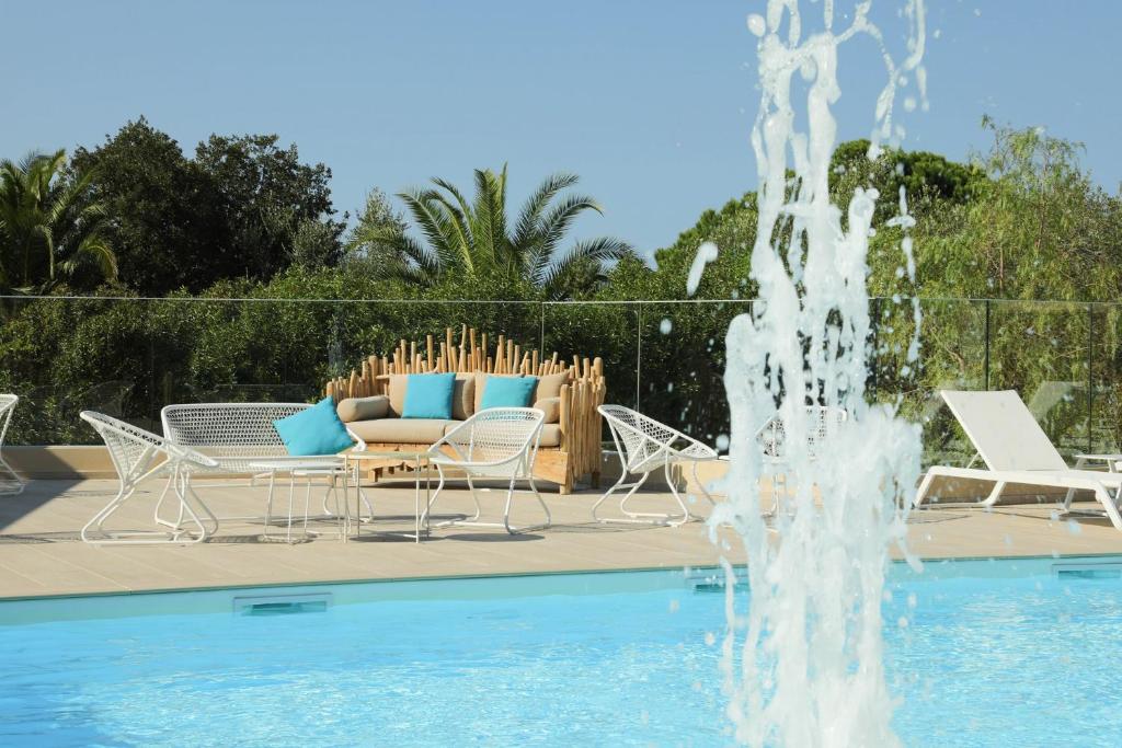 una fuente junto a una piscina con sillas y un sofá en Résidence Storia d'Estate en LʼÎle-Rousse