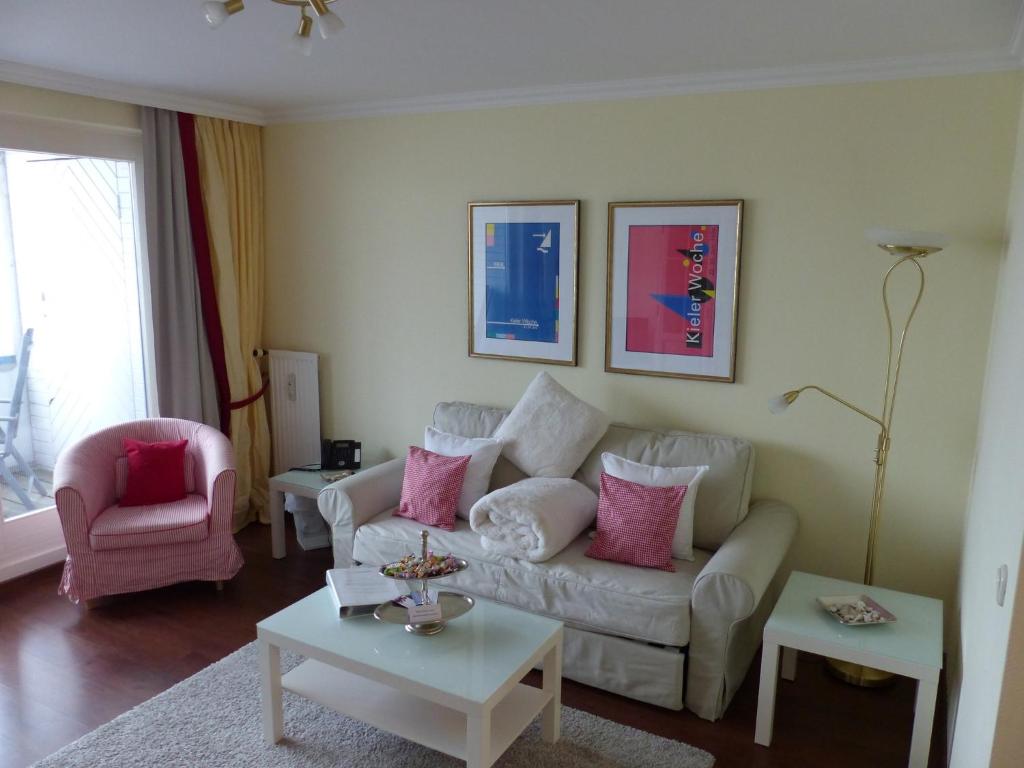 a living room with a white couch and pink pillows at FeWo J 24 in Laboe