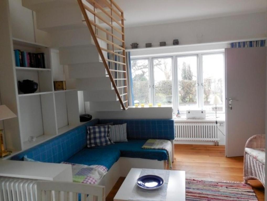 a living room with a blue couch and a staircase at Ferienhaus Schwille - Loft 2 in Westerbergen