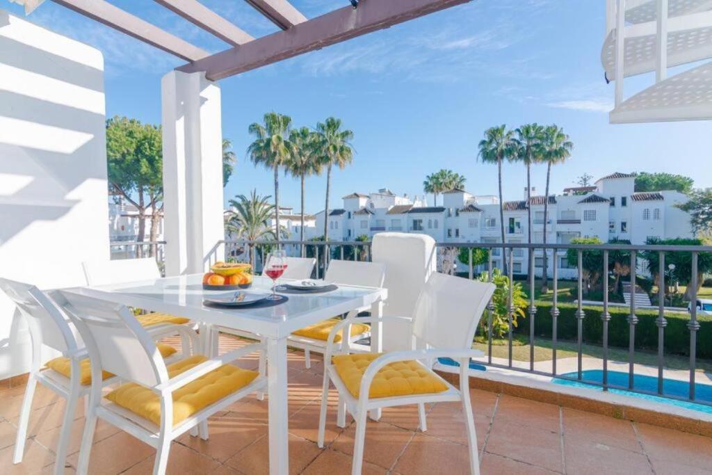 - une table à manger et des chaises blanches sur un balcon avec des palmiers dans l'établissement Modern Beach Side Duplex Penthouse, à Estepona