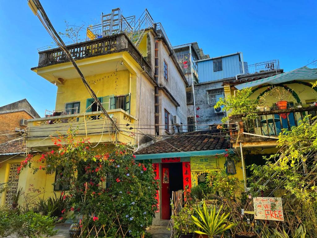 un edificio amarillo con una puerta roja y algunas plantas en Yellow House Hostel Huizhou West Lake en Huizhou