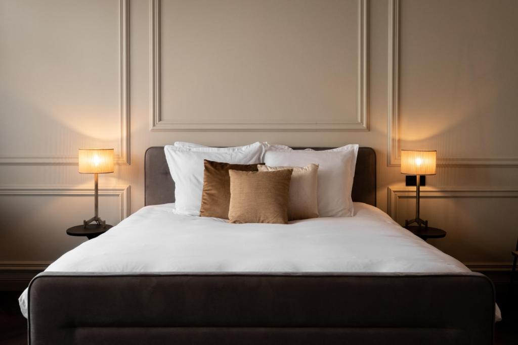a bedroom with a bed with pillows and two lamps at Boutique Hotel Huys Oud Teylingen in Warmond