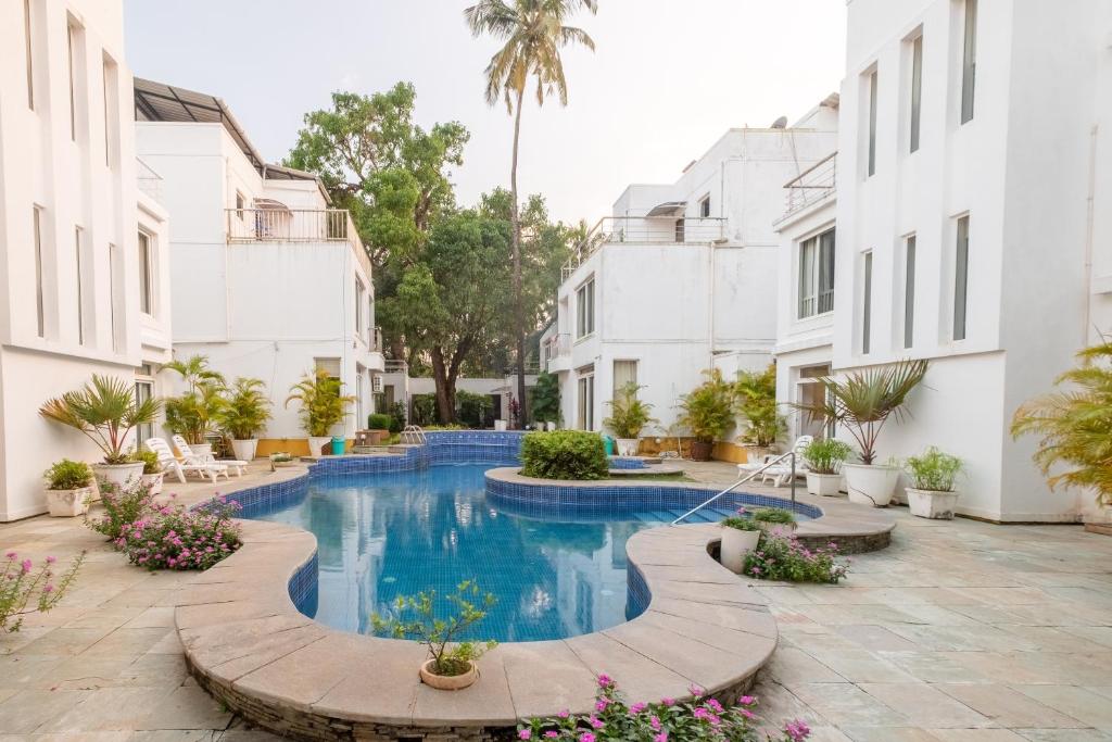 Snowdrop- Exquisite 3BHK Villa with Pool- Candolim By StayMonkey في كالانغيُت: مسبح في ساحة ذات مباني بيضاء