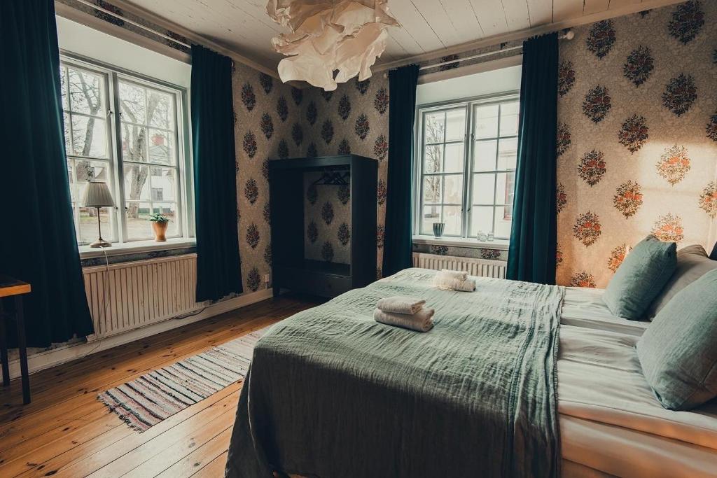 a bedroom with a large bed and two windows at Gysinge Wärdshus Hotell in Österfärnebo