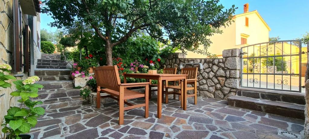 a wooden table and chairs on a stone patio at Apartment Mužić in Cres