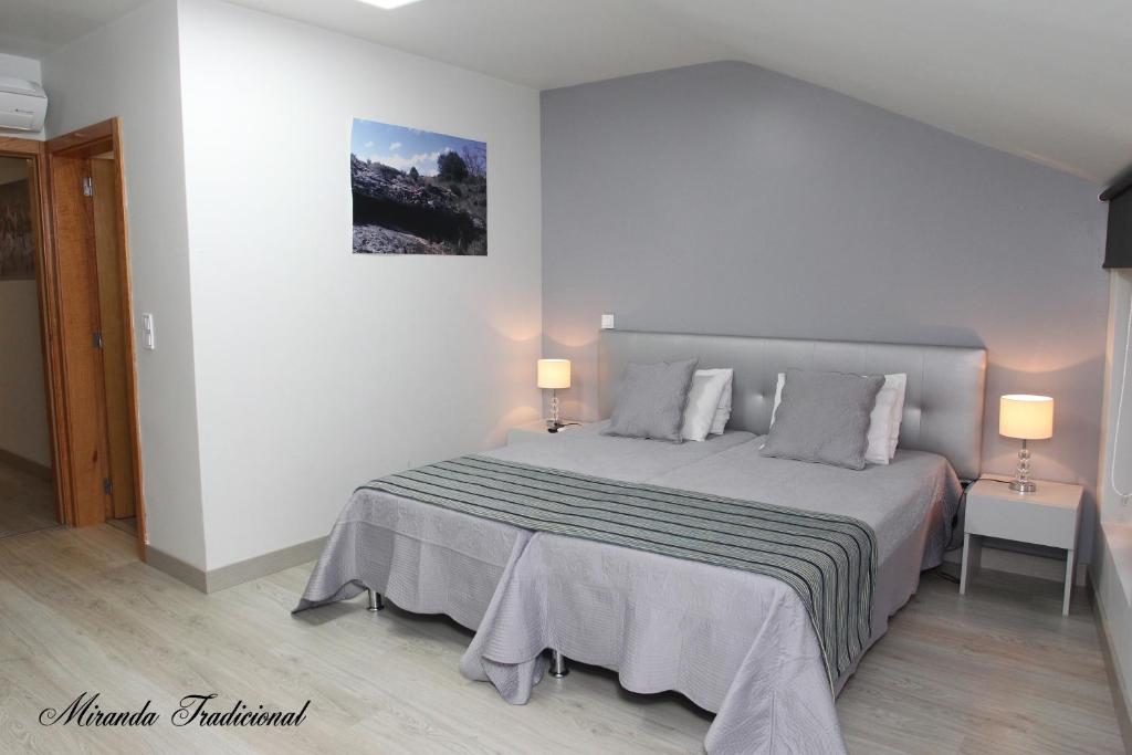 a bedroom with a large bed with two lamps at Miranda Tradicional in Miranda do Douro