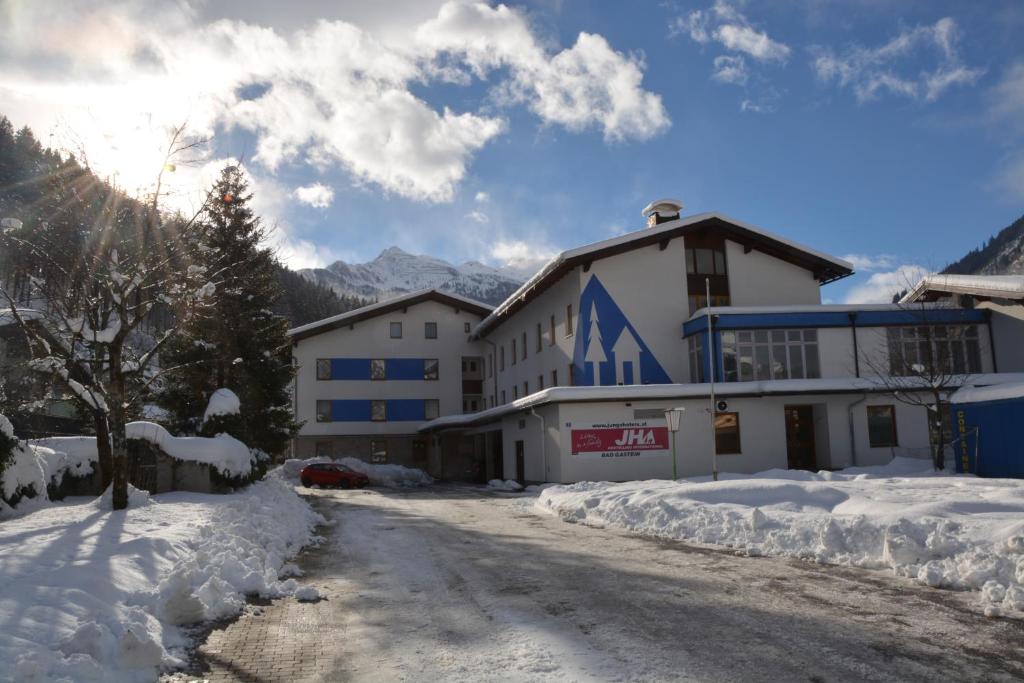 uma rua coberta de neve em frente a um edifício em Jugendherberge Bad Gastein em Bad Gastein