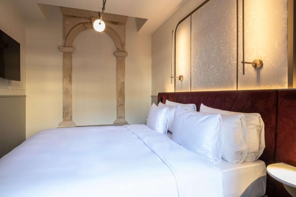 ヴェネツィアにあるLuxury Apartments Palazzo Naniの白いシーツと枕が備わったベッドのある寝室