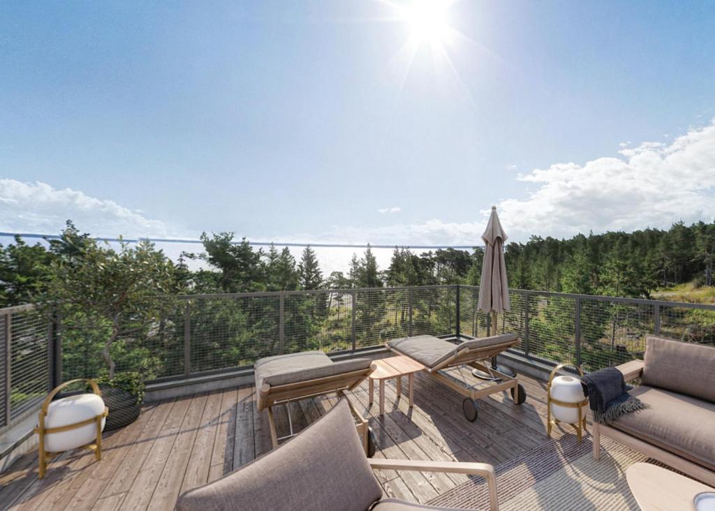 uma varanda com um sofá, uma mesa e um guarda-chuva em Västös Strand by FIRST Hotels em Lärbro