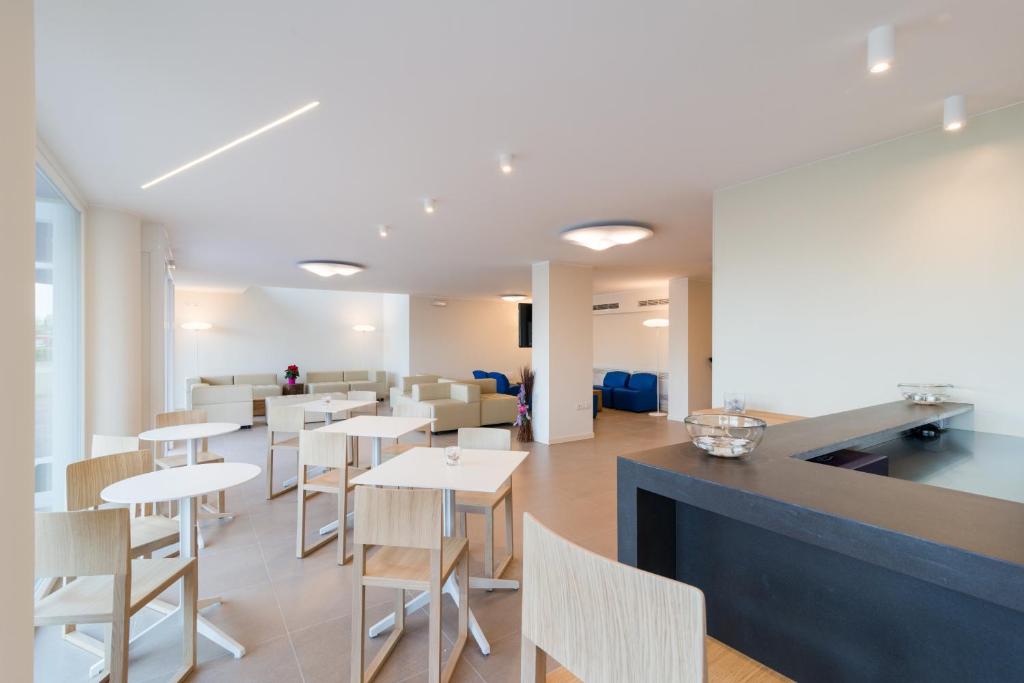 a restaurant with white tables and chairs and a counter at Hotel Mediterraneo in Sottomarina
