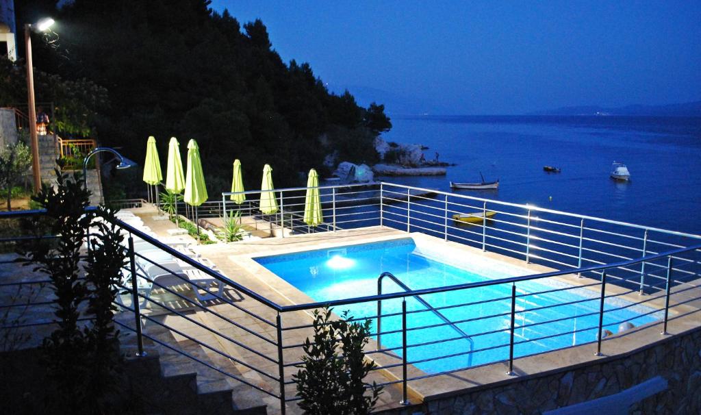 a swimming pool with a view of the ocean at night at Apartments Nostro in Omiš
