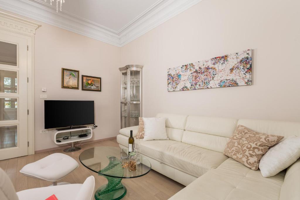 a living room with a white couch and a tv at Villa Sokol Apartments Opatija center in Opatija