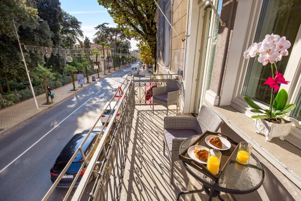 a balcony with a table and a car on the street at Villa Sokol Apartments Opatija center in Opatija